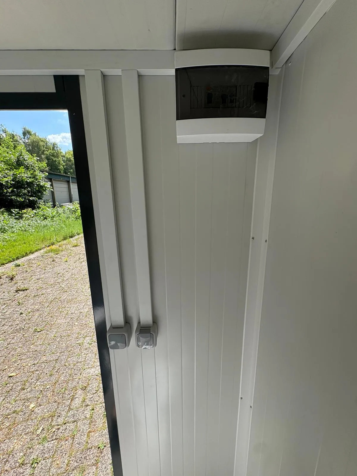Interior of a portable bathroom unit showing fuse box and light switch