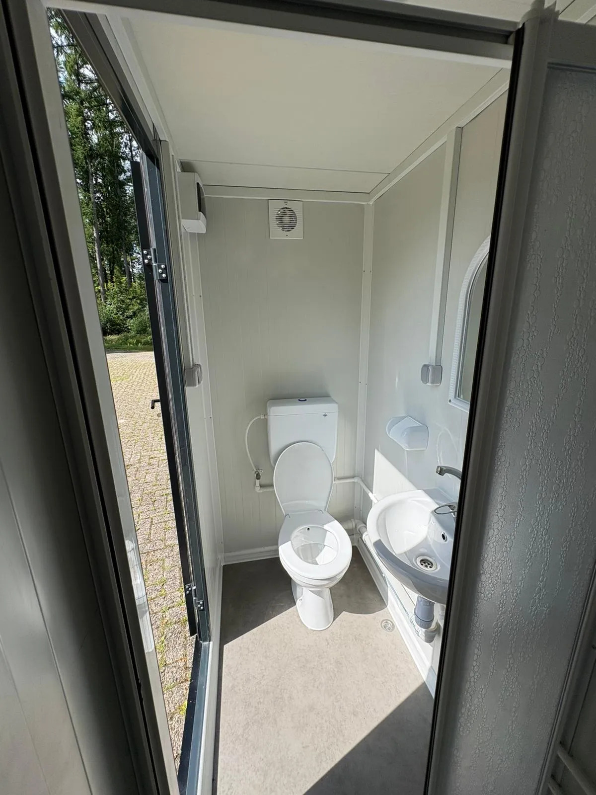 Interior of a portable bathroom unit showing toilet and sink