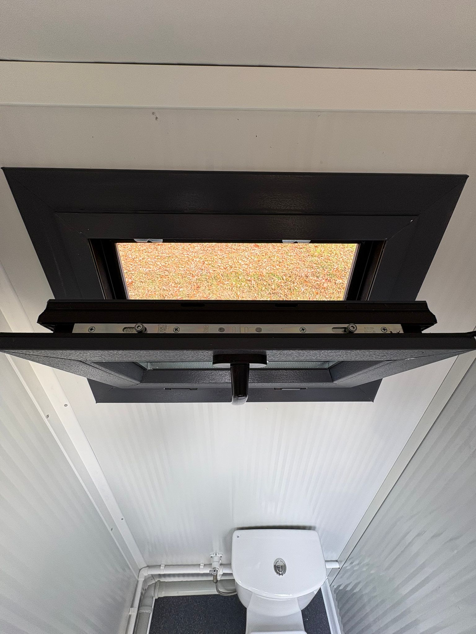 Openstaand draaikiepraam van een dubbele toiletunit.