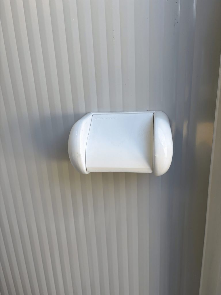 Toilet roll holder inside a portable toilet unit for camping