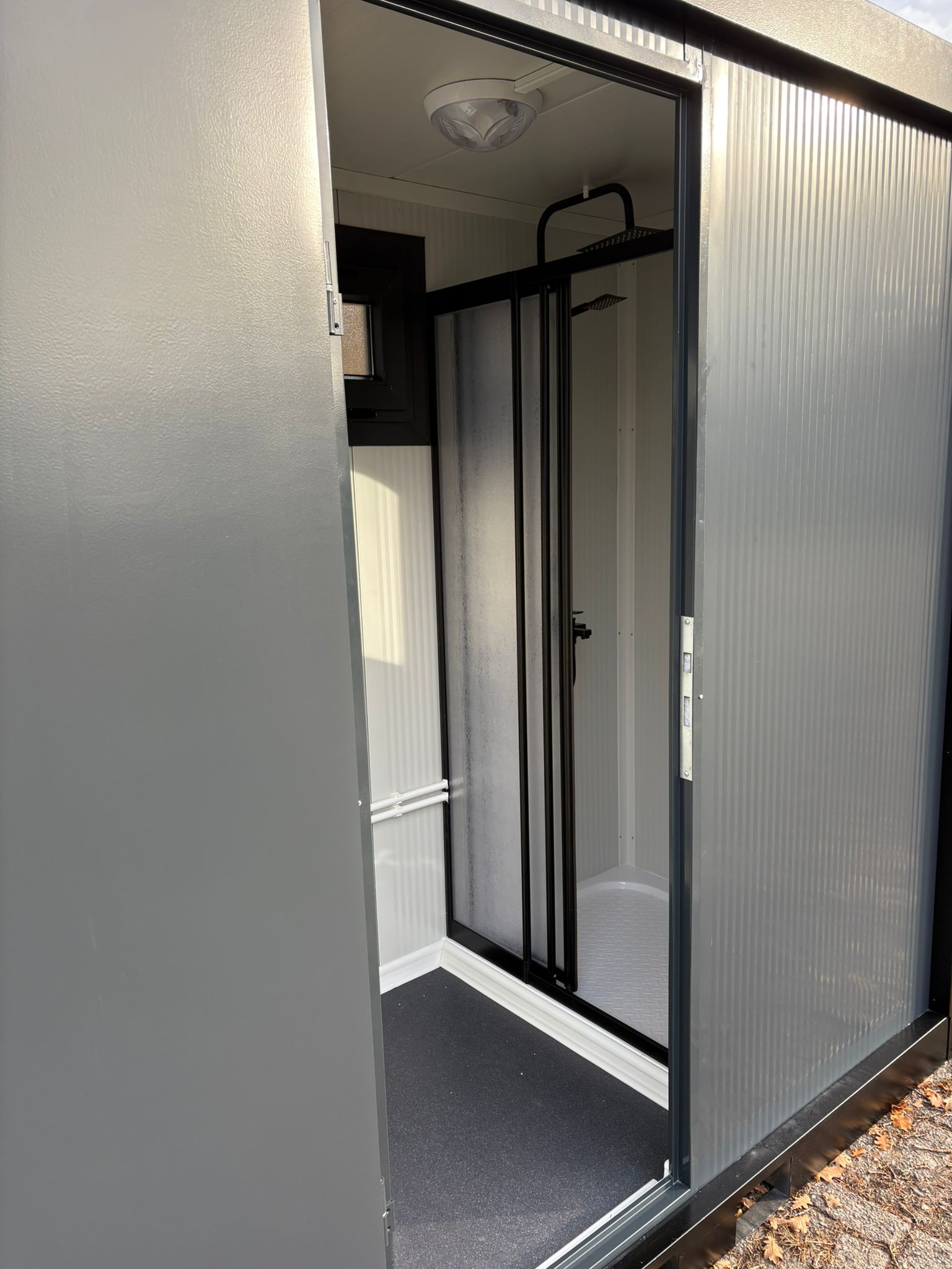 Inkijk door de deur van een doucheunit met omkleedruimte.