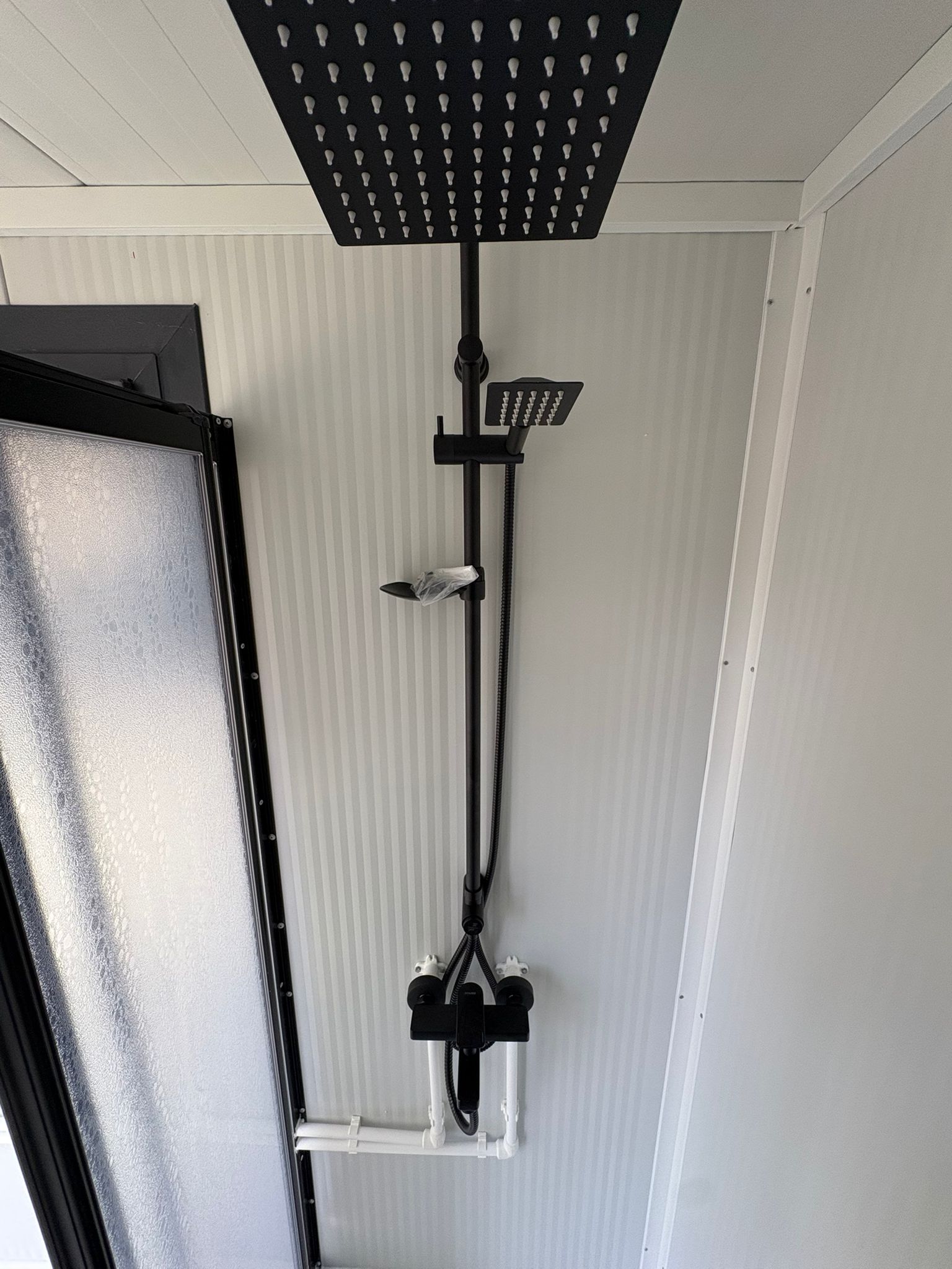 Douchestang en opstelling van een doucheunit met omkleedruimte.