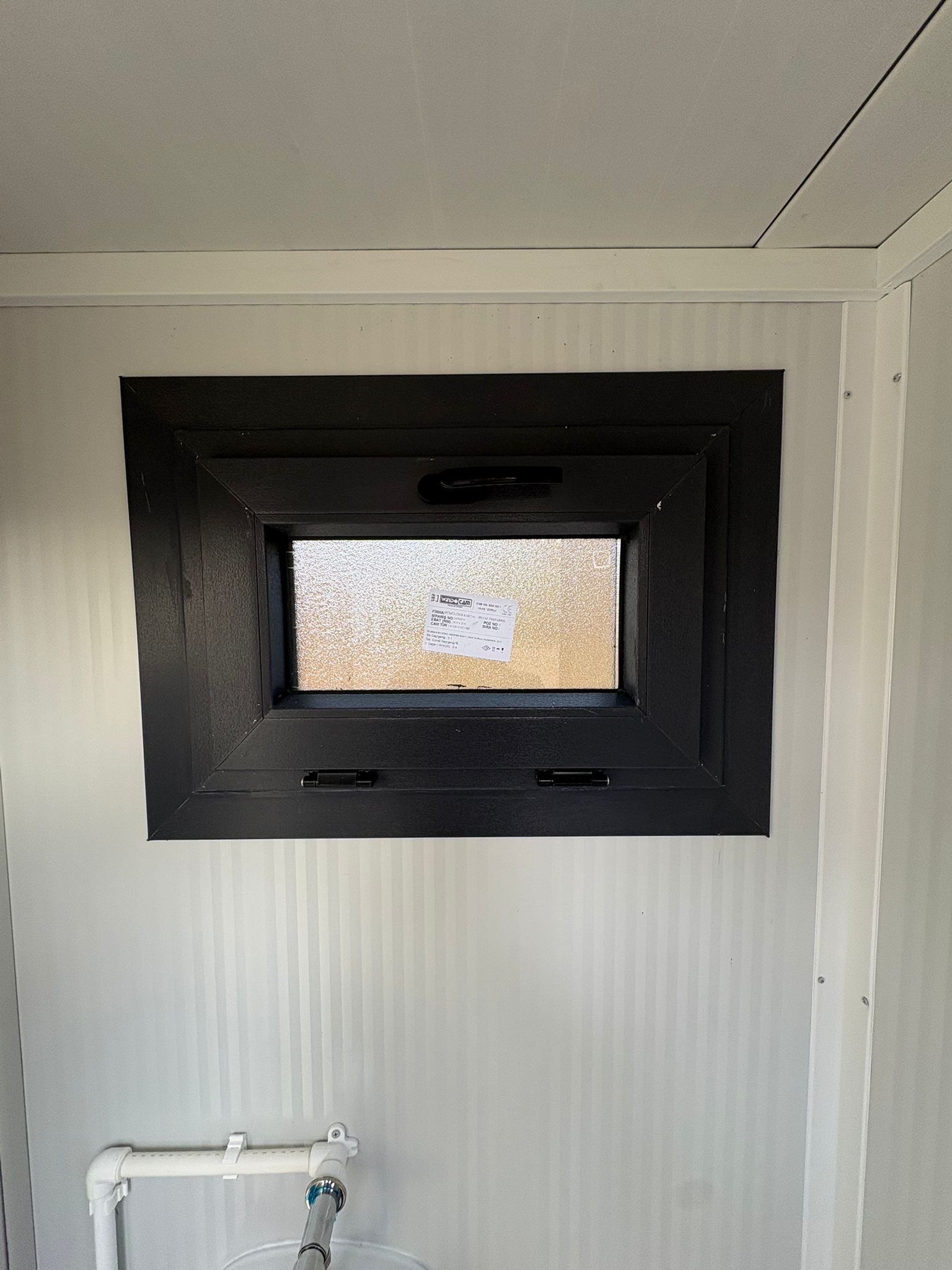 Dicht draaikiepraam aan de urinoirkant van een toilet- en urinoirunit.